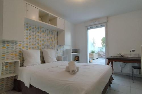 une chambre avec un grand lit blanc avec deux serviettes dessus dans l'établissement Dassaut - Toulouse - CI - 2 pièces spacieux avec grande terrasse et vue dégagée, à Toulouse