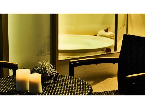 a table with two candles and a bathroom with a tub at Blanchette Nankishirahama - Vacation STAY 05733v in Kanayama