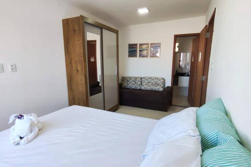 a bedroom with a large white bed and a living room at Apto em Ilhéus - Pé na areia in Ilhéus