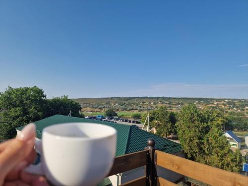 a person holding a cup of coffee on a balcony at La Banel Hotel in Selemet