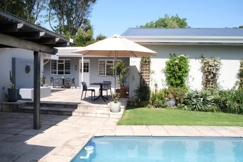 a backyard with a pool and an umbrella at High Hedges Guest Suites Constantia in Cape Town