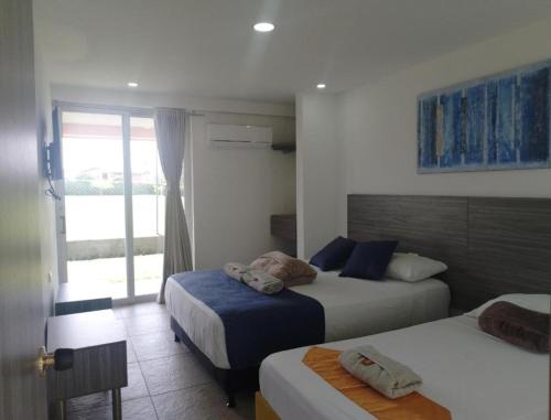 a hotel room with two beds and a window at HOTEl PALO GRANDE CF PEREIRA in Pereira