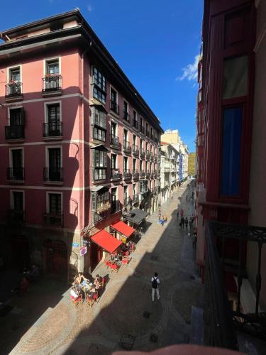 an empty city street with buildings and tables and people at Casual Fuentes in Bilbao