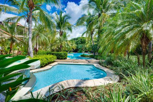 a pool with palm trees in a resort at Pacifico Townhouse 106 in Coco
