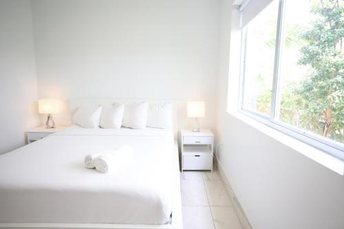 a white bedroom with a white bed and a window at Family Friendly Condo Steps to Miami Beach with Free Parking in Miami Beach