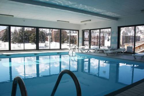 une grande piscine avec des chaises et des fenêtres dans l'établissement Demi-Chalet 6 à 8 pers, proche piste, à Saint-Étienne-en-Dévoluy
