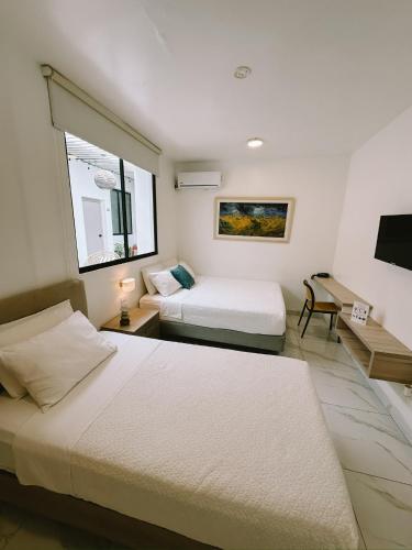ein Hotelzimmer mit zwei Betten und einem Fenster in der Unterkunft Manakin Hostal & Resto in Manta
