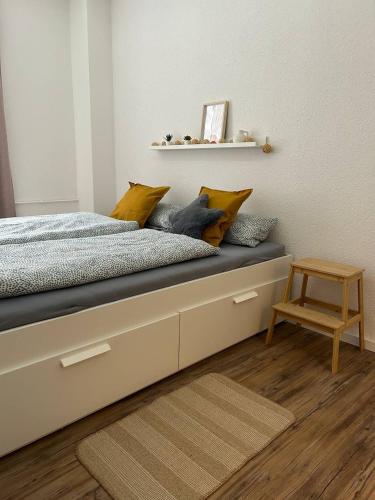 a bedroom with a bed with yellow pillows and a stool at Modernes Apartment - Leipzig Alt-West in Leipzig