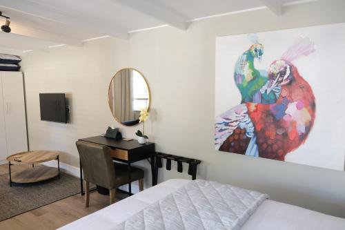 a bedroom with a bed and a desk and a mirror at High Hedges Guest Suites Constantia in Cape Town