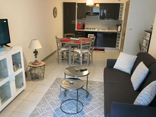 un salon avec un canapé et une table avec des chaises dans l'établissement Appartement L Hippocampe, à Granville