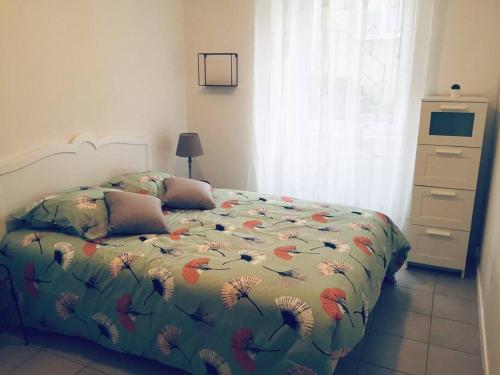 une chambre avec un lit avec une couette fleurie dans l'établissement Appartement L Hippocampe, à Granville