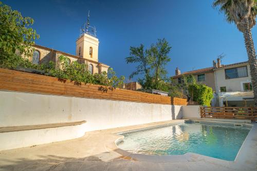 une piscine en face d'un bâtiment avec une tour d'horloge dans l'établissement Splendide love room Moments collection, au Beausset