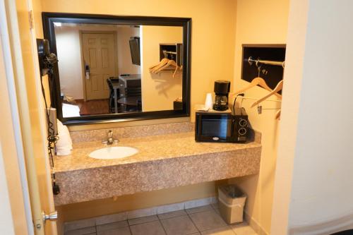 a bathroom with a sink and a mirror and a microwave at Colonial Inn Hammond in Hammond