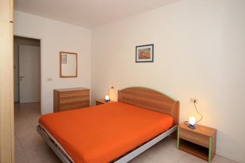 - une chambre avec un lit orange et 2 tables de nuit dans l'établissement Residence Cristoforo Colombo, à Caorle