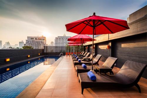 einen Pool mit Stühlen und Sonnenschirmen auf einem Gebäude in der Unterkunft Hotel Solo, Sukhumvit 2, Bangkok - SHA Extra Plus in Bangkok