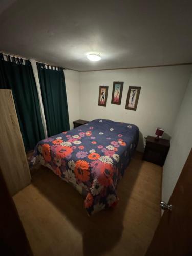 a bedroom with a bed with a floral comforter at ripamontilodge in Coquimbo