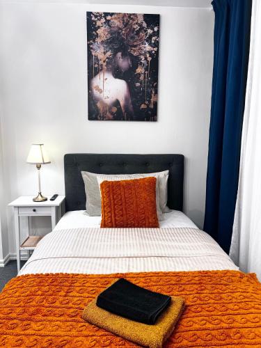 a bedroom with a bed with a black and orange blanket at Noah Longstay Nämndemansgatan 52 A-B in Borås