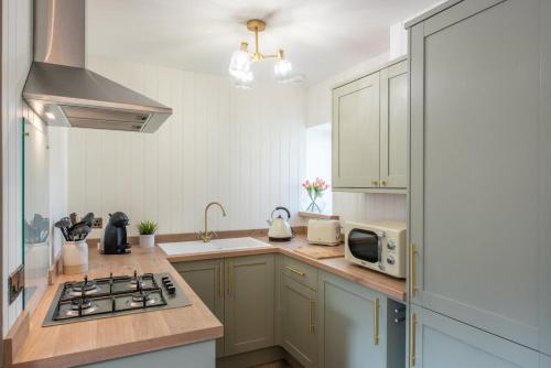 a kitchen with a stove top oven next to a microwave at Mabels Cottage by the beach in Nairn