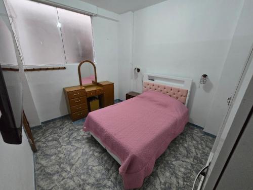 a small bedroom with a pink bed and a dresser at Céntrico departamento en el Piso 1 in Tacna