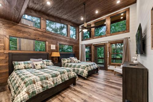 two beds in a room with wooden walls and windows at Teresa's River Retreat in Blue Ridge