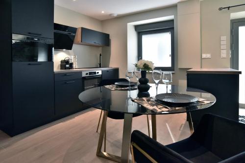 une cuisine avec une table à manger et une cuisine avec des armoires noires dans l'établissement Cocöon Rance, à Plouër-sur-Rance