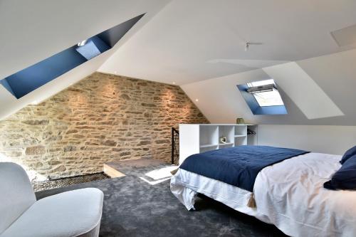 Un dormitorio con una cama y una pared de piedra. en Cocöon Rance, en Plouër-sur-Rance