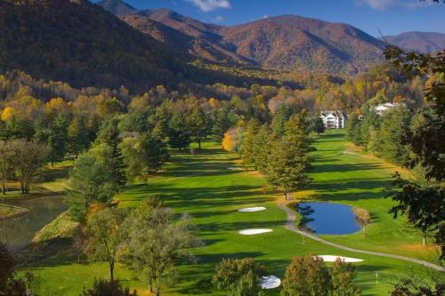 a golf course with a pond and mountains in the background at Beautiful Log Cabin with Panoramic Views in Maggie Valley