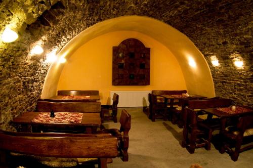 Apartments Rakoczi في زيلينا: مطعم بطاولات وكراسي خشبية في جدار حجري
