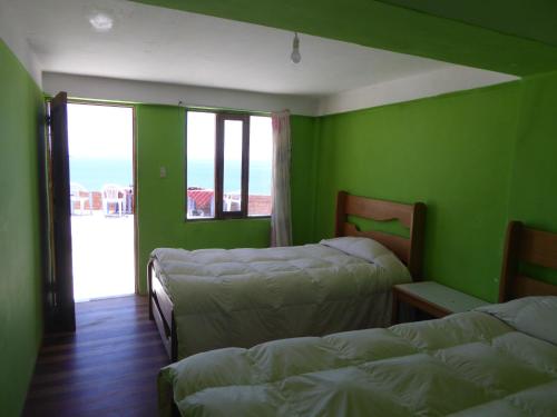 two beds in a room with green walls at Hostal Amanecer in Comunidad Yumani