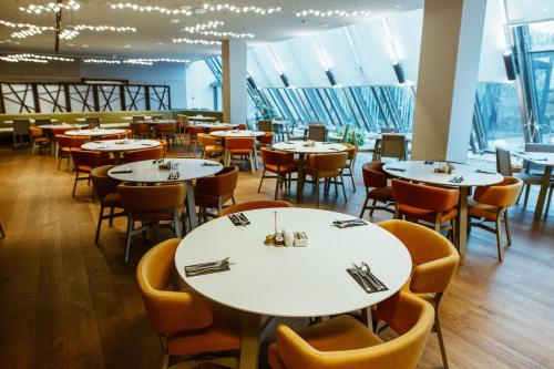 a restaurant with white tables and chairs and windows at Crowne Plaza Belgrade by IHG in Belgrade