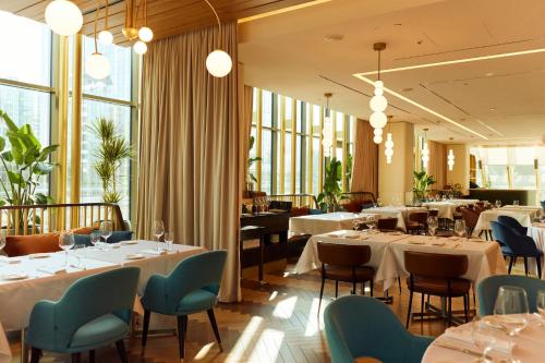 a restaurant with white tables and chairs and windows at Crowne Plaza Belgrade by IHG in Belgrade