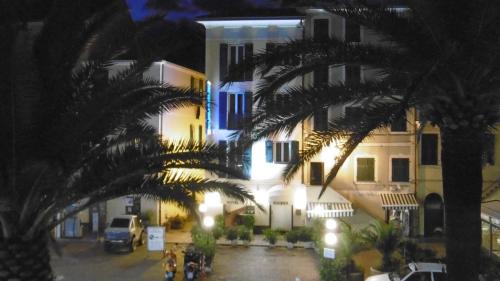 a city street at night with palm trees and buildings at Hotel Riviera in Arenzano