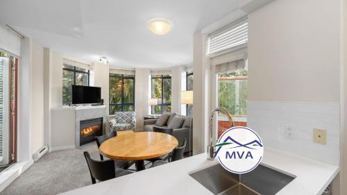 a kitchen and living room with a table and chairs at Alpenglow Lodge Two Bedroom Apartment with Private Hot Tub by MVA in Whistler