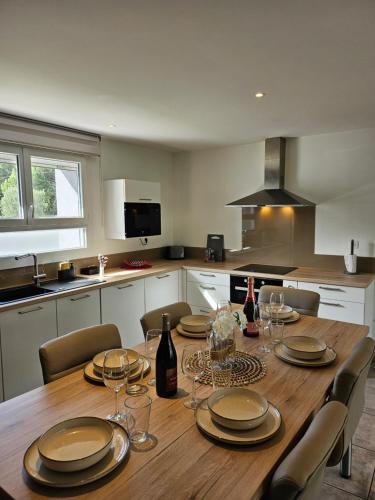 - une cuisine avec une table en bois, des assiettes et des verres à vin dans l'établissement Magnifique maison avec baignoire balnéo, à Cornebarrieu