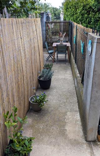 a patio with a table and potted plants and a fence at Appart moderne proche plage avec terrasse et climatisation in Hyères