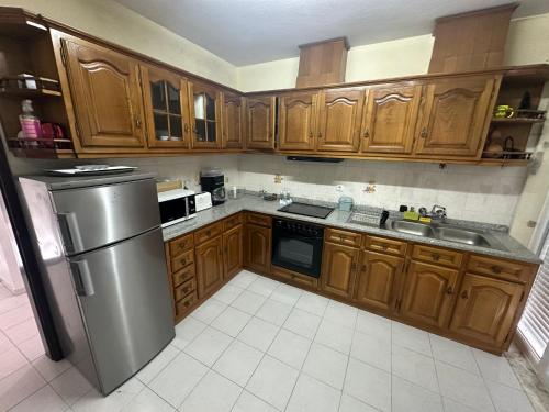 a kitchen with wooden cabinets and a stainless steel refrigerator at Casa do Cruzeiro - Favaios in Favaios