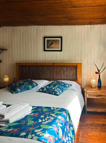 a bedroom with a bed and a picture on the wall at Hotel El Abrazo del Arbol in Mindo