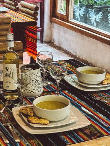 a table with a bowl of soup and wine glasses at Hotel El Abrazo del Arbol in Mindo