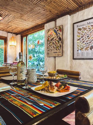 a table with a plate of food and a bottle of wine at Hotel El Abrazo del Arbol in Mindo