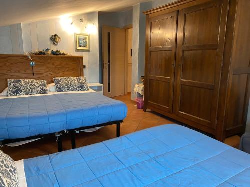 a bedroom with two beds and a wooden cabinet at B&B Torre in Langa in Carrù