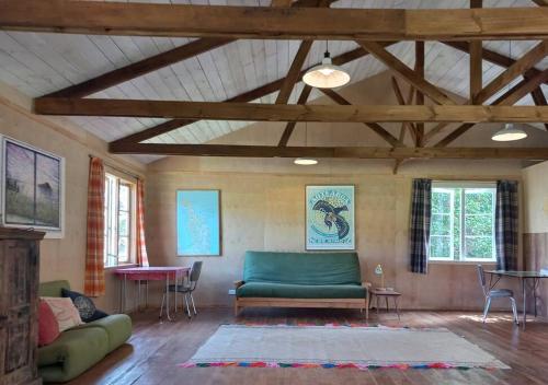 a living room with a green couch and a rug at The Woolshed, Papa Aroha, Coromandel in Moturua Island