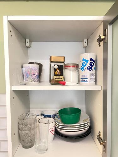 a cabinet filled with dishes and other kitchen items at Fanta flat France Suisse in Saint-Louis
