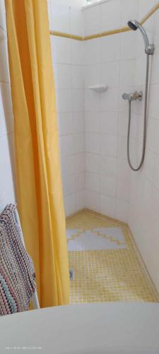 La salle de bains est pourvue d'une douche avec rideau de douche jaune. dans l'établissement Appartement avec jardin à Saint Jean d'Illac, à Saint-Jean-dʼIllac