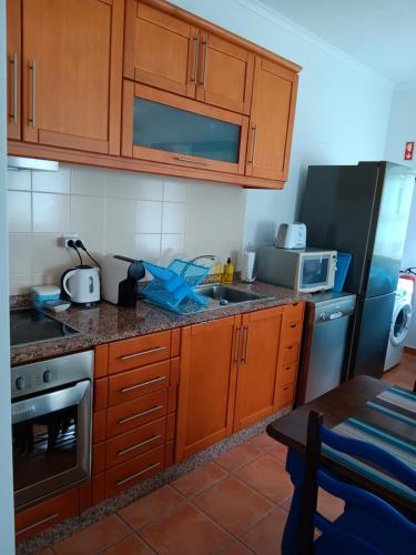 a kitchen with wooden cabinets and a sink and a refrigerator at Casinha de férias no campo - Quintinha dos Cavalos - Arruda dos Vinhos in Sabugos