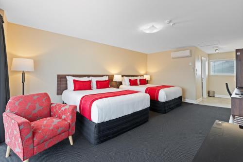 a hotel room with two beds and a chair at Newina Rotorua in Rotorua