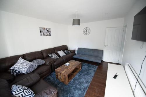 a living room with a brown couch and a coffee table at Spacious 3 Bed Home Manchester Airport Free Parking in Manchester