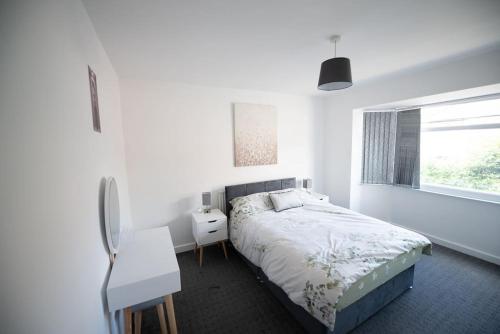 a bedroom with a bed and a desk and a window at Spacious 3 Bed Home Manchester Airport Free Parking in Manchester
