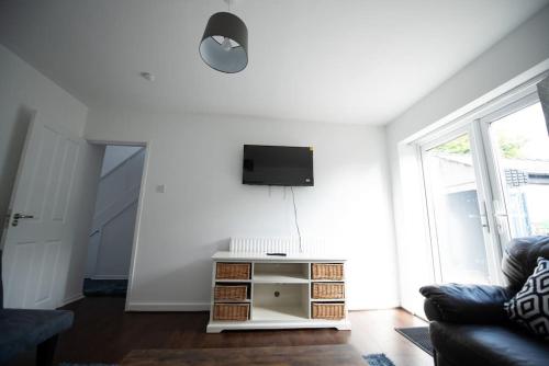 a living room with a couch and a tv on a wall at Spacious 3 Bed Home Manchester Airport Free Parking in Manchester