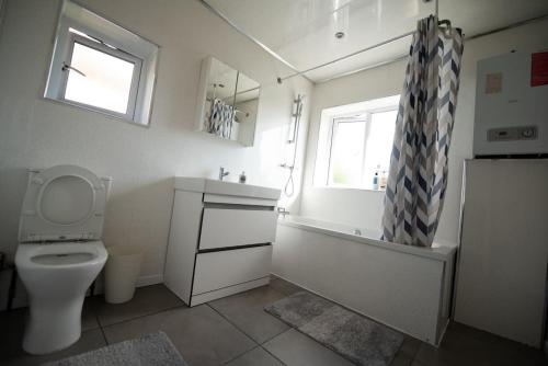 a bathroom with a toilet and a tub and a window at Spacious 3 Bed Home Manchester Airport Free Parking in Manchester