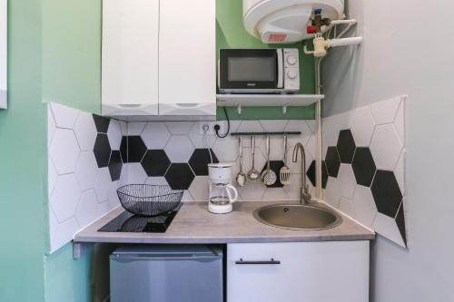 une petite cuisine avec un évier et un micro-ondes dans l'établissement Le Jardin d'Amiens 2 pers 8 min Centre ville & Gare, à Amiens